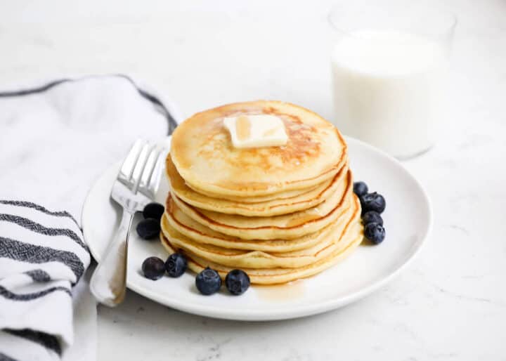 plate of ricotta pancakes with butter, syrup and blueberries 