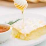 drizzling honey onto baked brie with a honey dipper