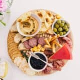 round charcuterie board with crackers, meats, cheeses and dips