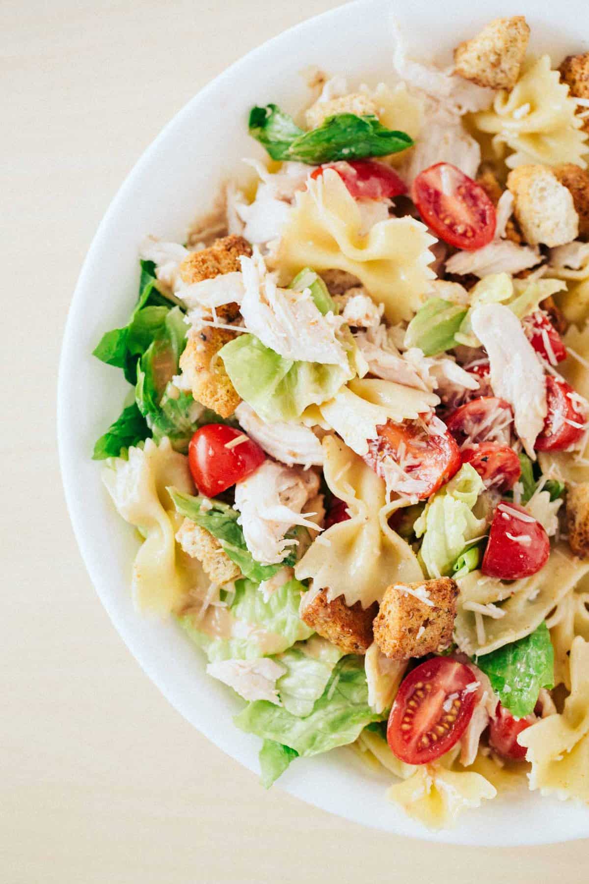 Chicken caesar pasta salad in white bowl.