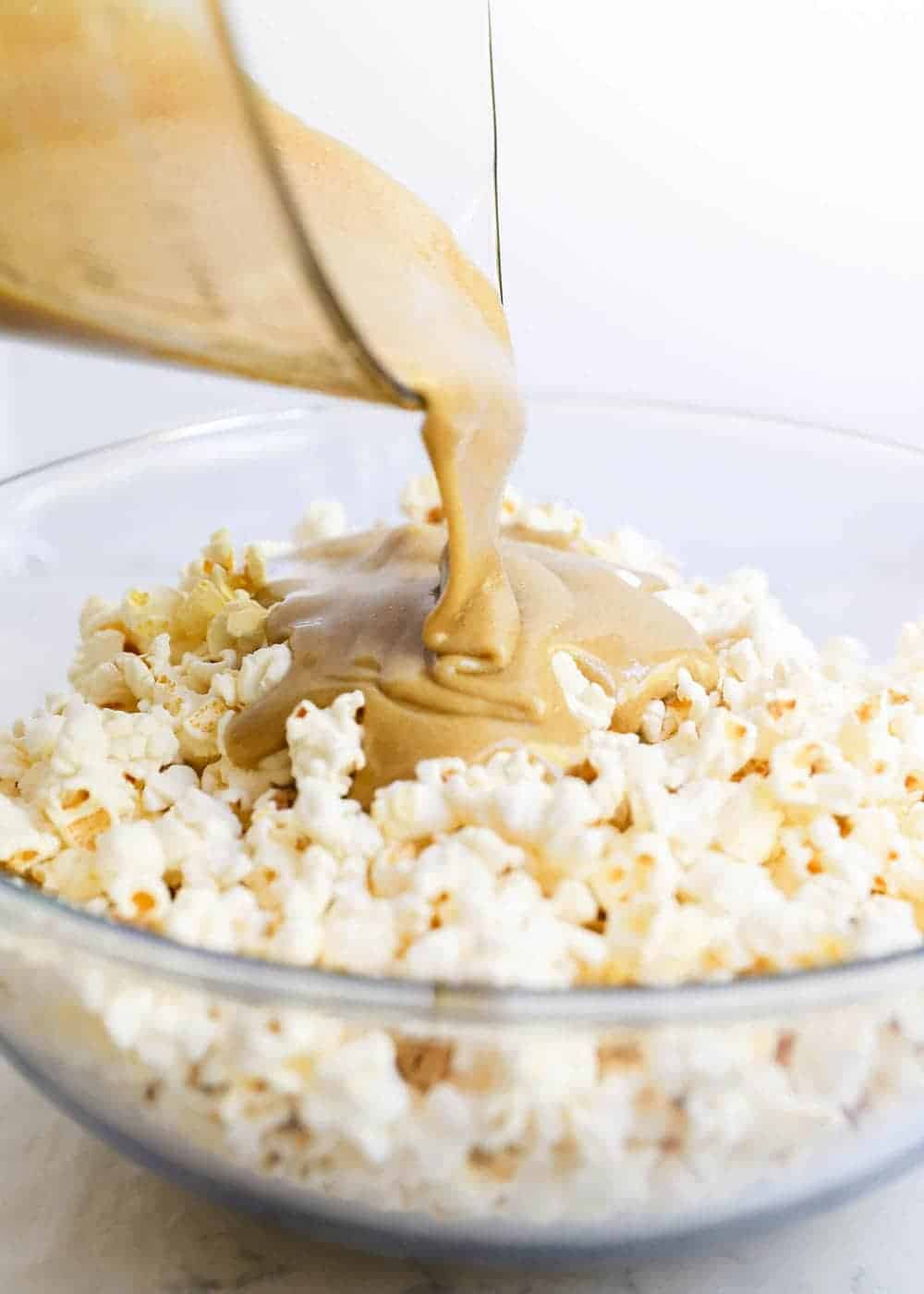 Pouring caramel into bowl of popcorn.