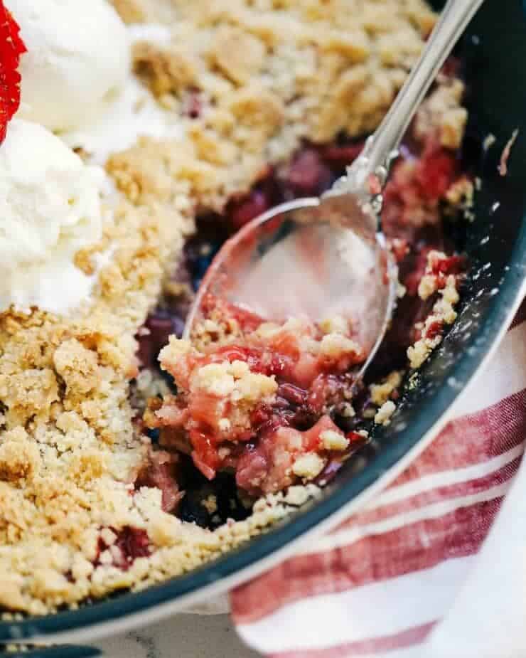 scooping out strawberry rhubarb crisp with a spoon 