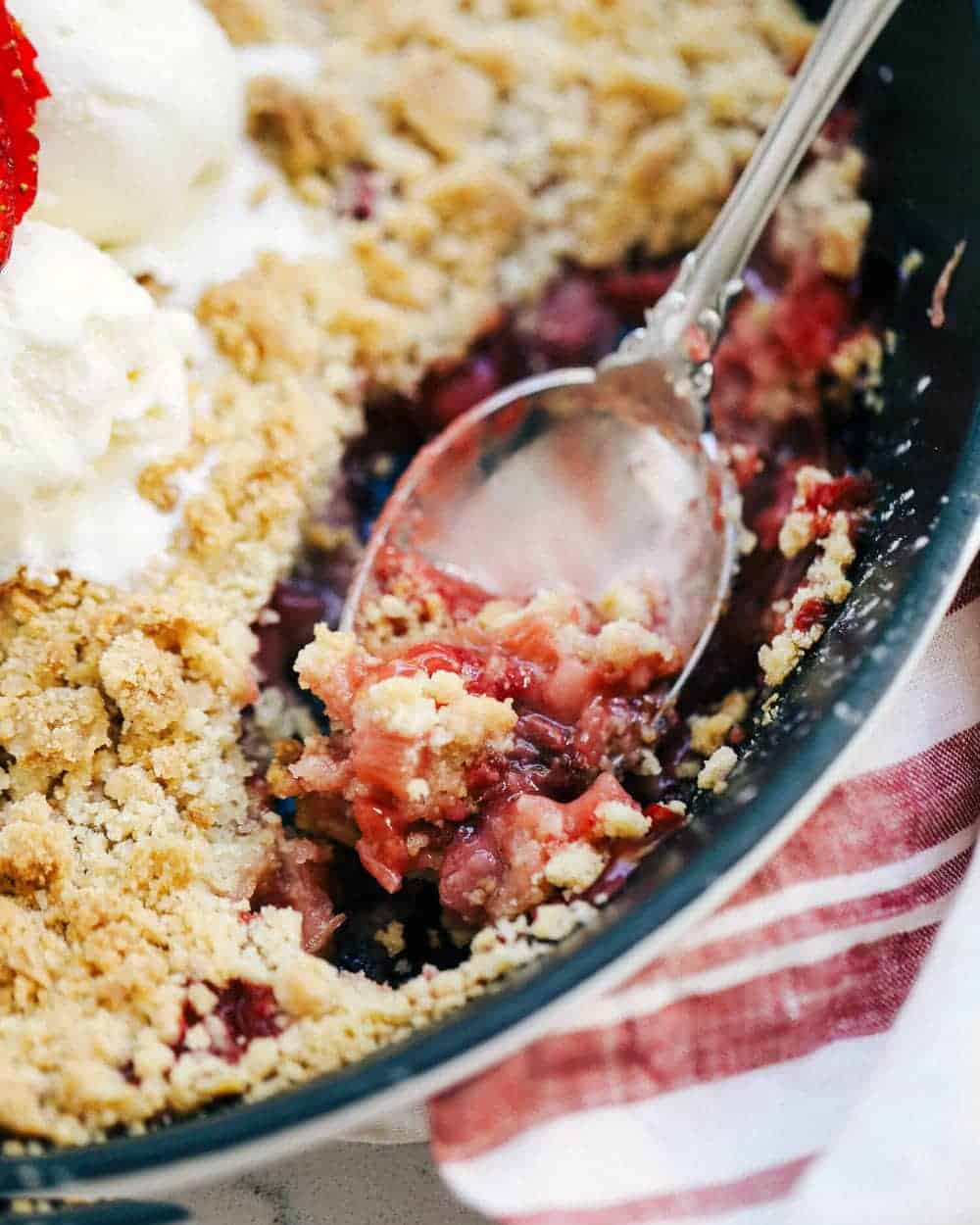 Scooping out strawberry rhubarb crisp with a spoon.