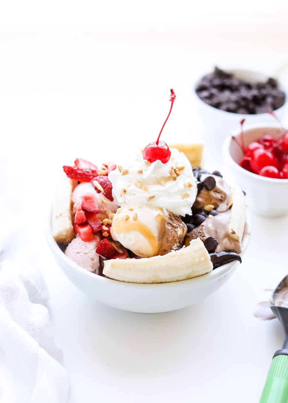 Banana split dessert in a white bowl.