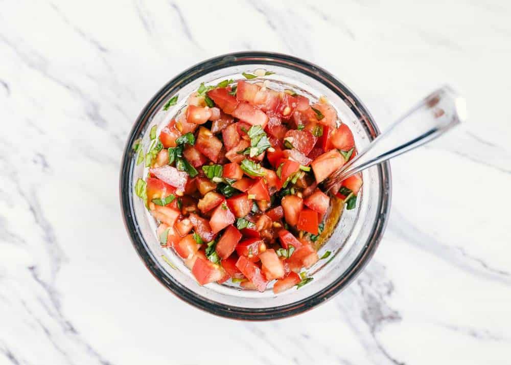 Homemade bruschetta in a bowl with a spoon.