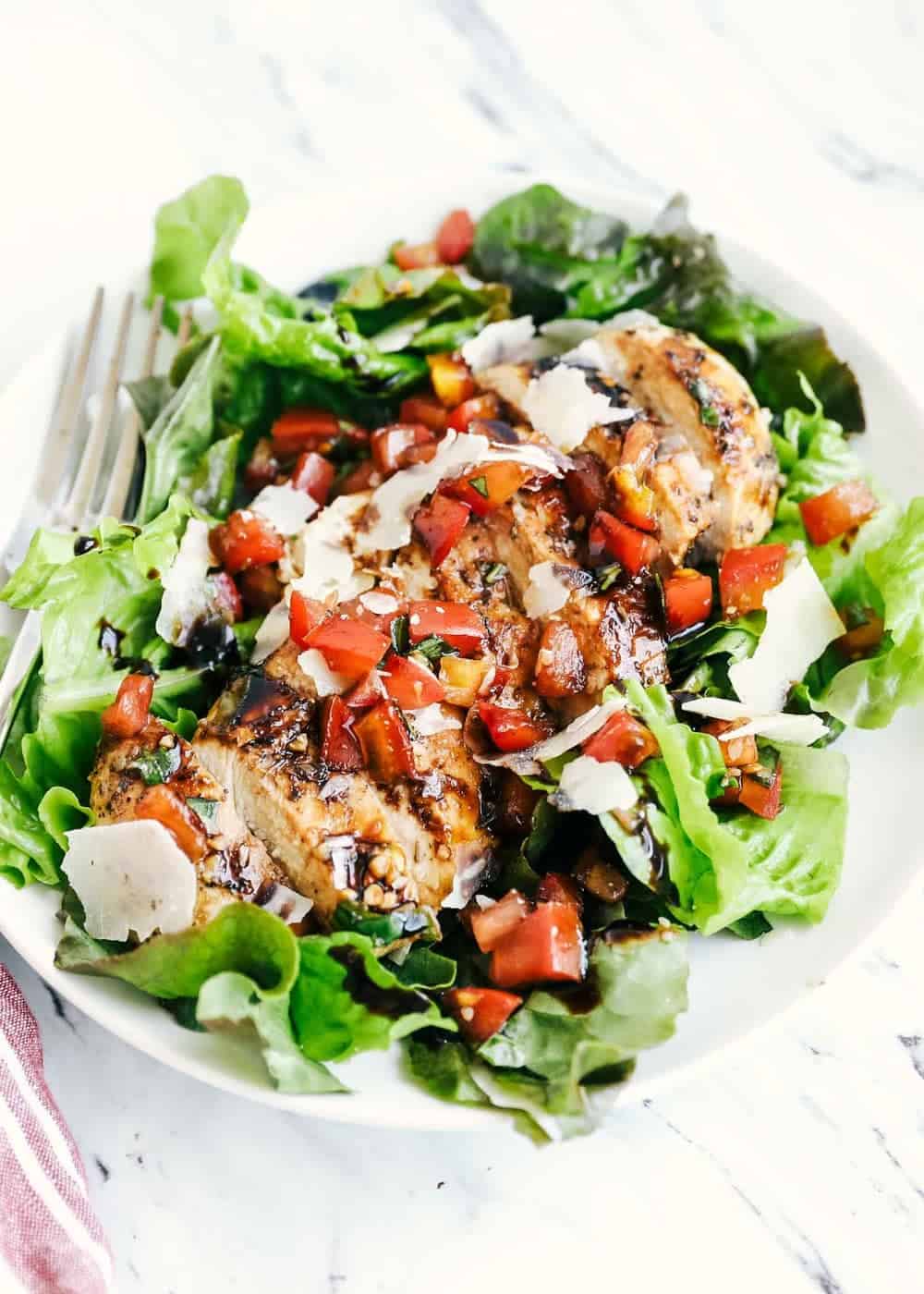 Bruschetta chicken on a bed of lettuce.