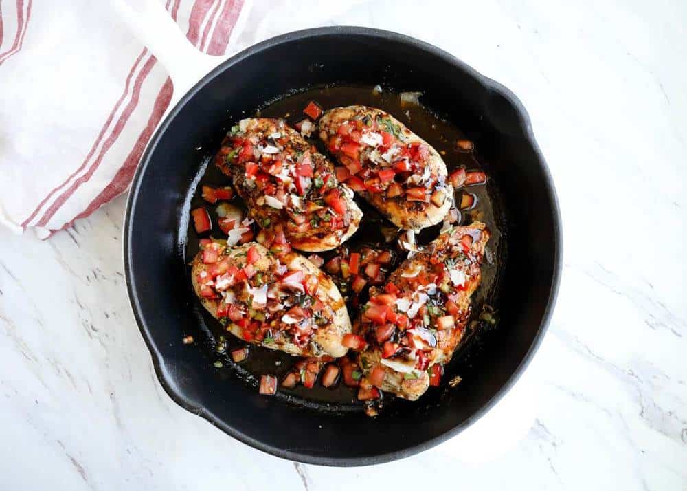 This bruschetta chicken is made with tender seared chicken topped with a homemade bruschetta made with fresh tomatoes, basil, garlic, olive oil and balsamic vinegar. Bruschetta chicken in a cast iron skillet.