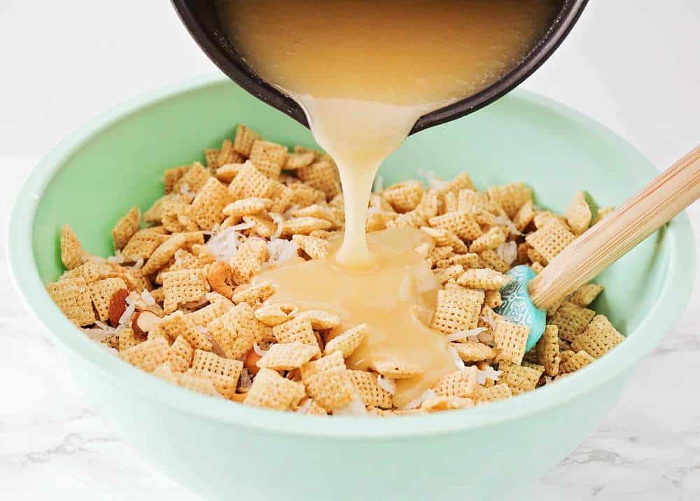 Pouring the sugar mixture over Chex mix.