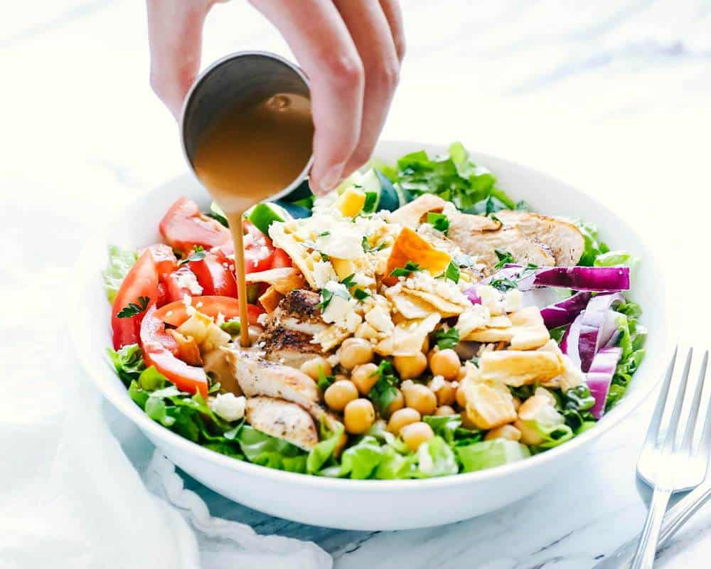 Pouring balsamic over mediterranean salad.