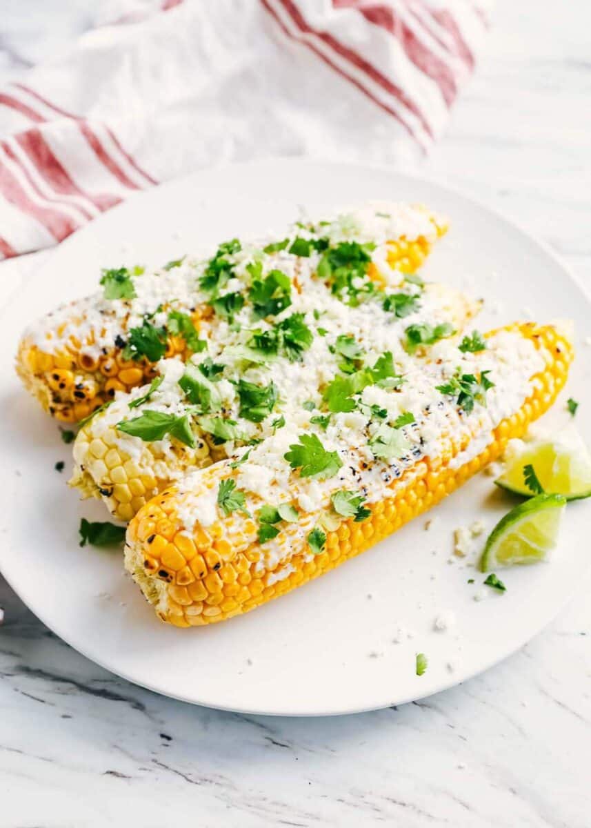 Mexican corn with cilantro on white plate 