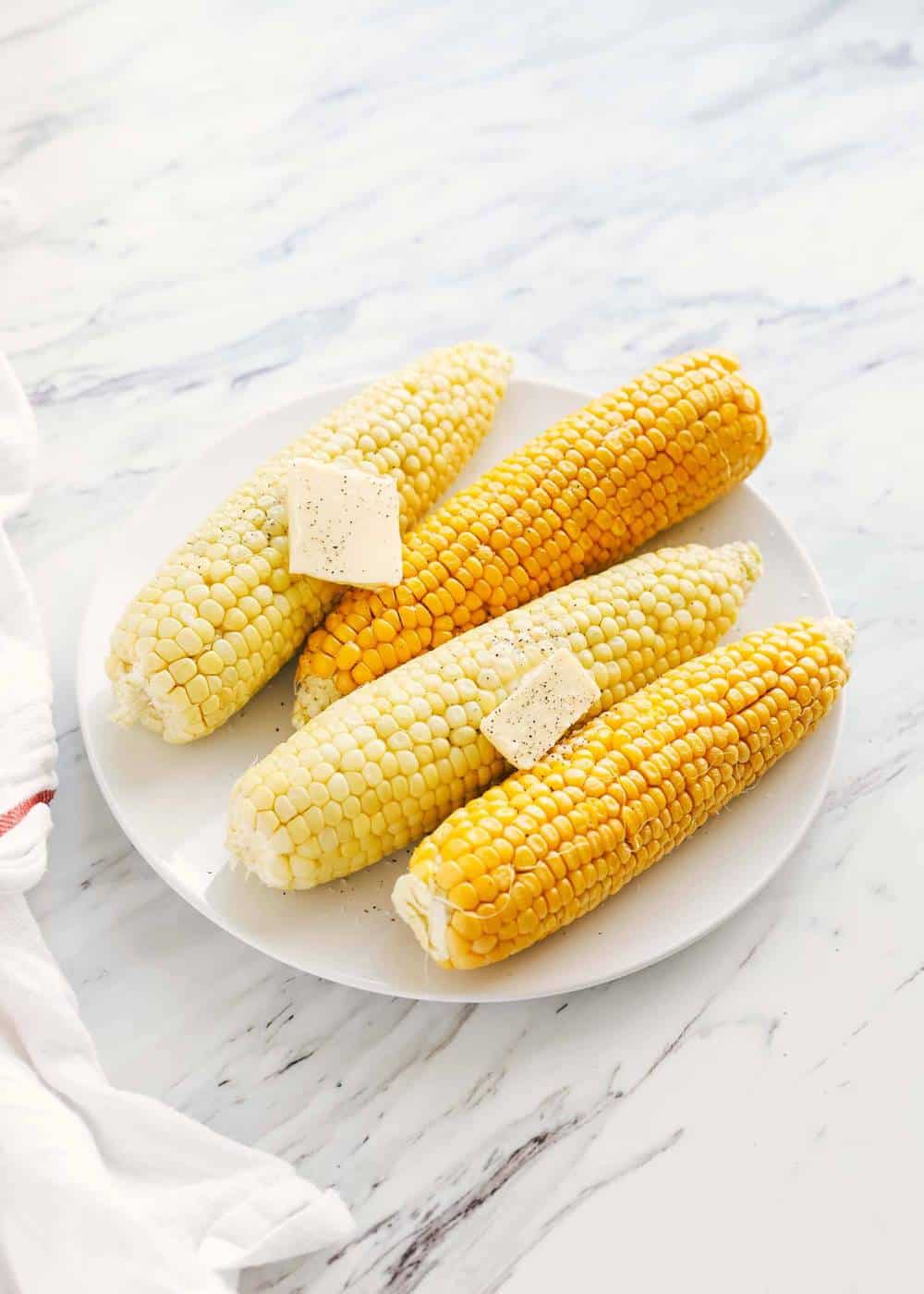 Microwave corn on the cob on a white plate.