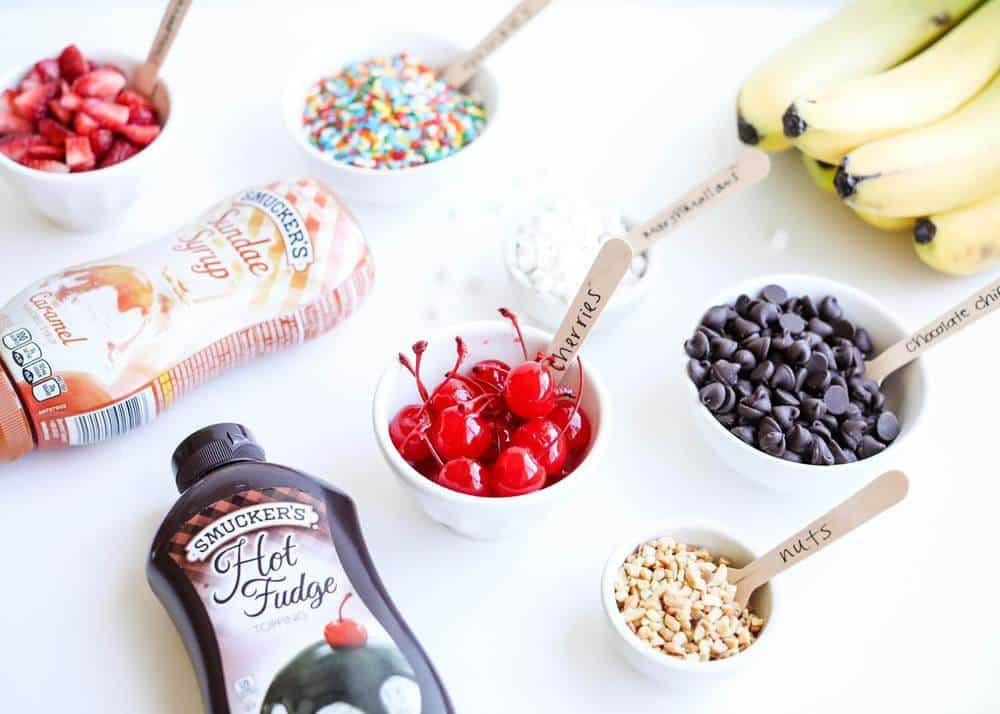 Banana split toppings in bowls on counter.