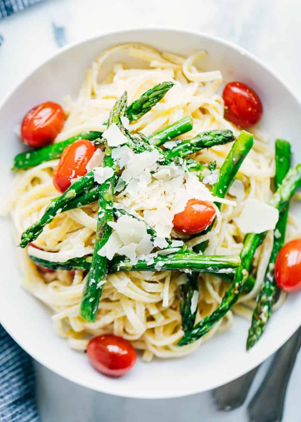 Bowl of asparagus pasta with shaved parmesan on top.