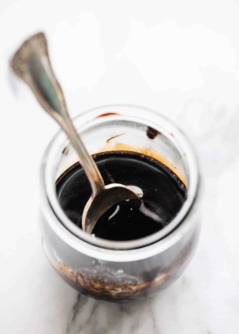 Jar of balsamic reduction with a spoon in it. 