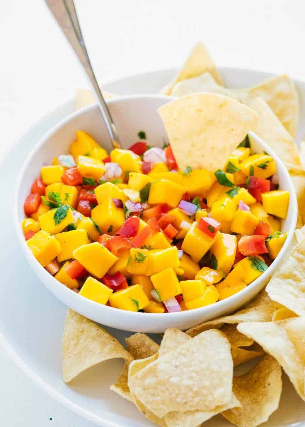 The BEST mango salsa that's fresh, full of flavor and combines a little heat with a little sweet. This easy recipe makes the perfect snack, appetizer or topping! Mango salsa served with tortilla chips.