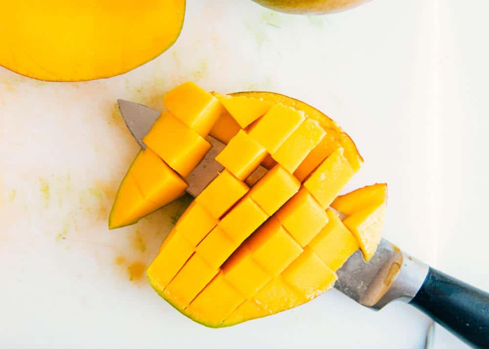The BEST mango salsa that's fresh, full of flavor and combines a little heat with a little sweet. This easy recipe makes the perfect snack, appetizer or topping! Slicing a mango into cubes.