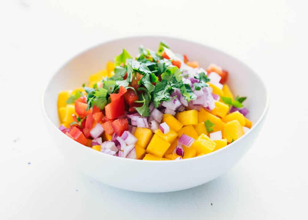 The BEST mango salsa that's fresh, full of flavor and combines a little heat with a little sweet. This easy recipe makes the perfect snack, appetizer or topping! Ingredients for mango salsa in a bowl.