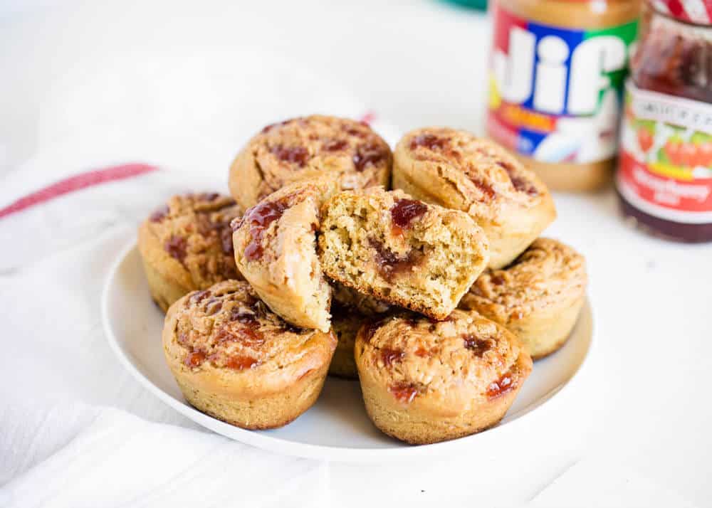 Peanut butter and jelly muffins stacked on a white plate.