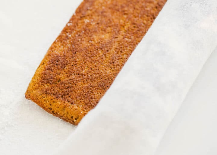 Delicious layers of fluffy pumpkin cake and sweet cream cheese filling swirled together to make the ultimate treat! This easy pumpkin roll is perfect to serve during the fall season. rolling pumpkin cake with tea towel