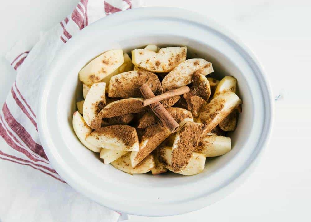 Sliced apples and spices in crockpot.
