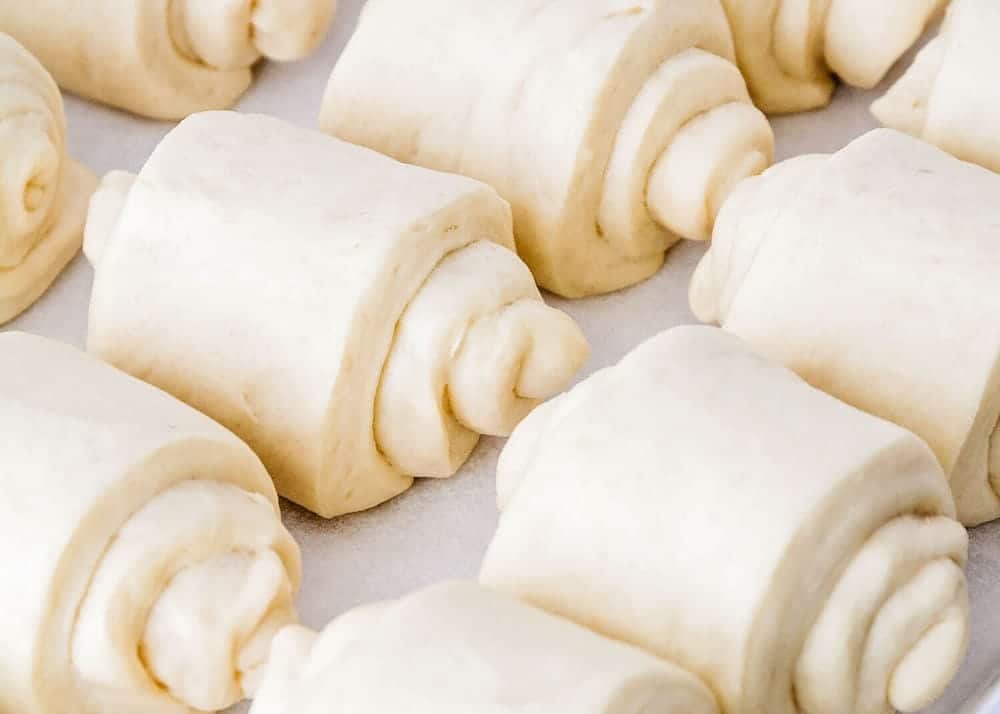 Unbaked lion house rolls lined on a baking sheet. 