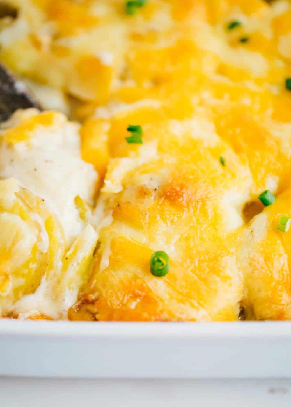 cheesy scalloped potatoes in a baking dish with chives on top 