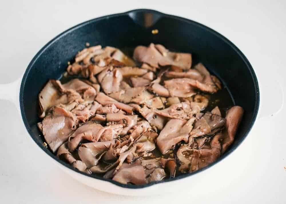 Roast beef in a pan with au jus sauce.
