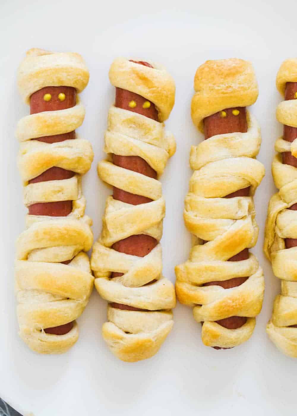These mummy hot dogs are the easiest Halloween appetizer that takes only 2 ingredients to make! So fun, festive and delicious. Serve with spooky spider web sauce for the ultimate Halloween experience! Halloween mummy hot dogs.