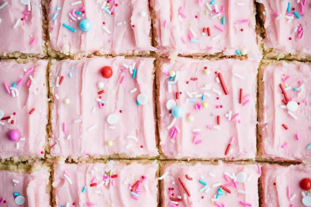 Sugar cookie bars with pink frosting and sprinkles.