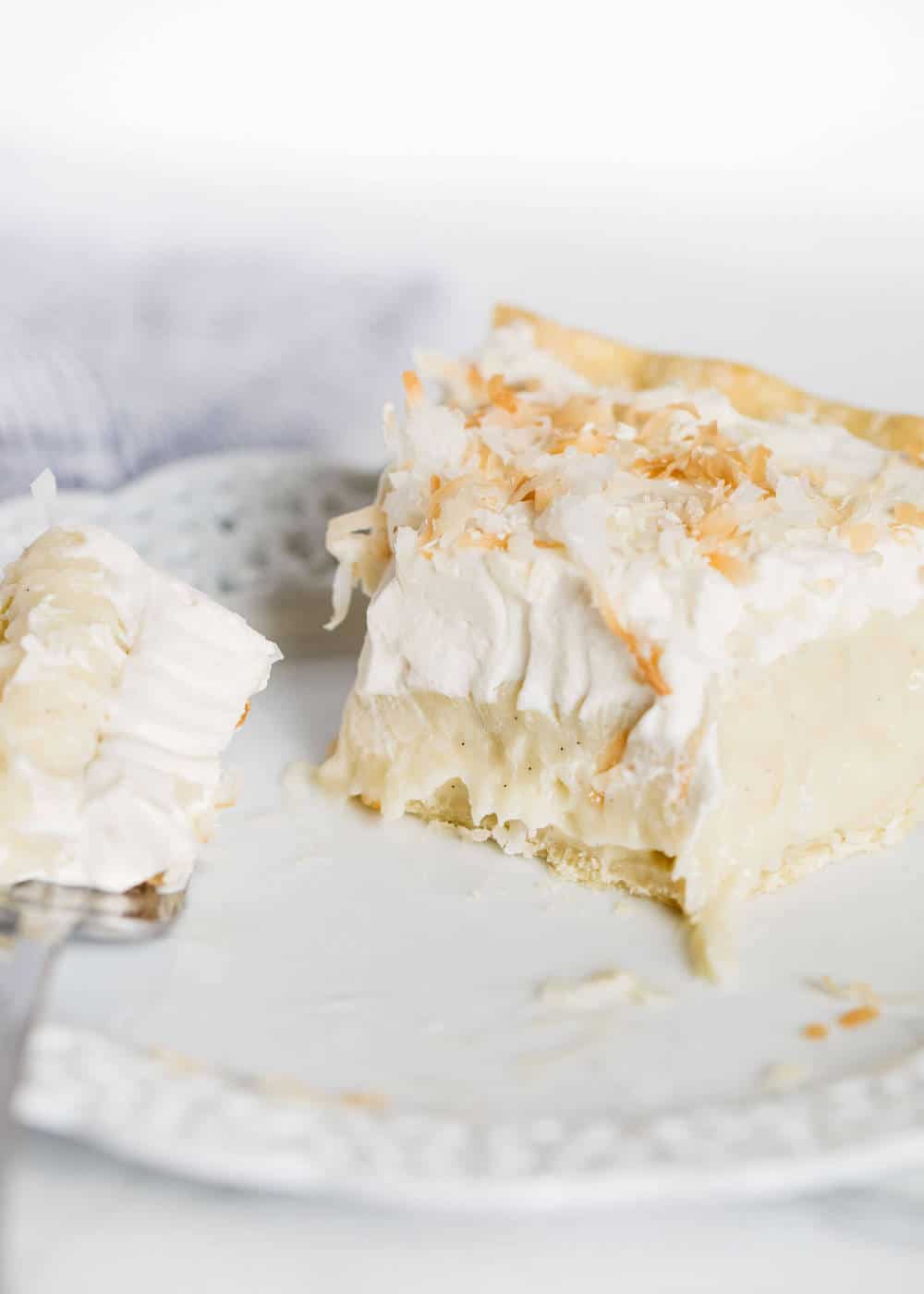 Slice of coconut pie with bite taken out.