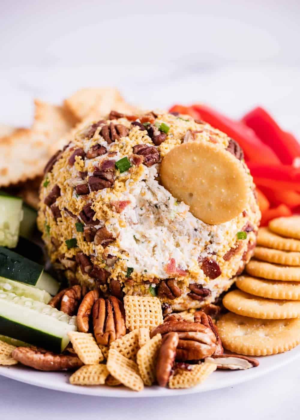 Cheese ball recipe with bacon on a plate with crackers and veggies.