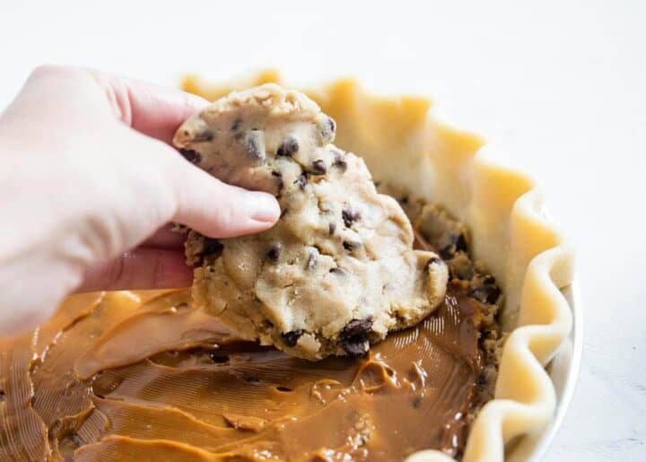 adding chocolate chip cookie dough on top of pie crust 