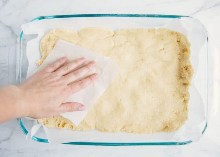 pressing sugar cookie dough into baking dish 