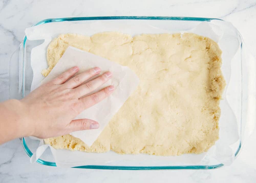 Pressing sugar cookie dough into the baking dish.