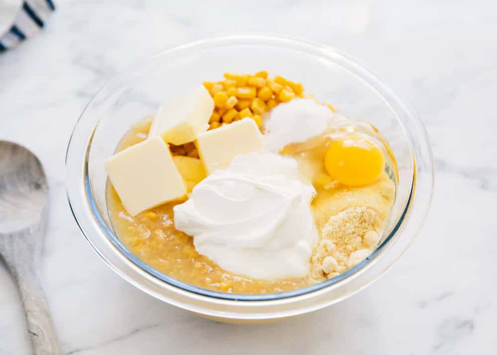 Corn casserole ingredients in glass bowl.