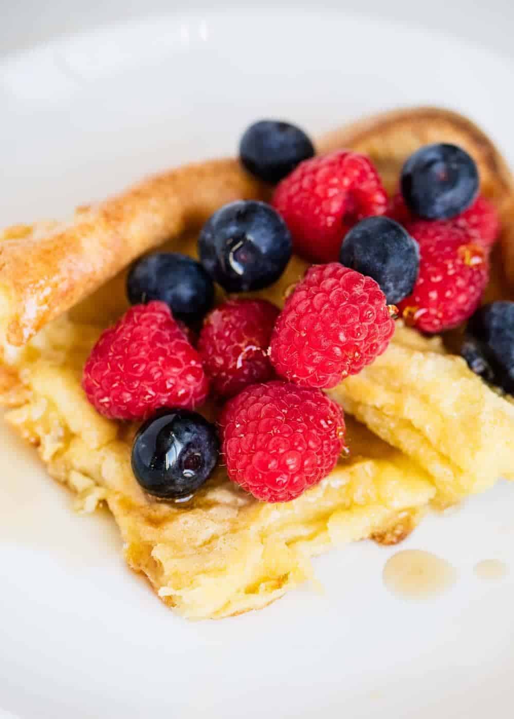 German pancakes topped with syrup and berries.