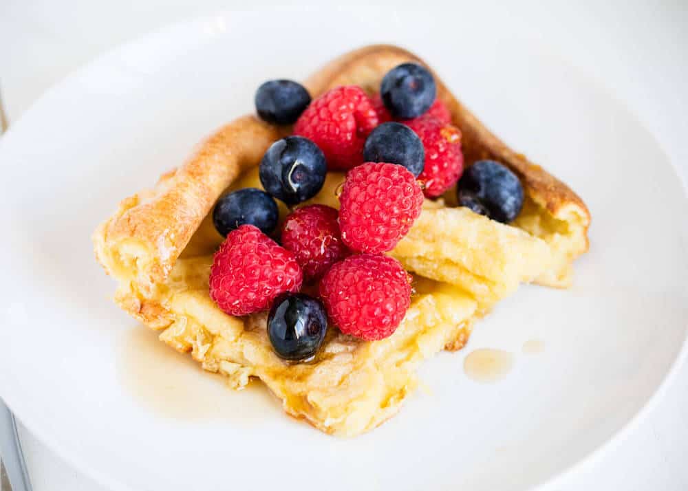 German pancakes with berries on a white plate.