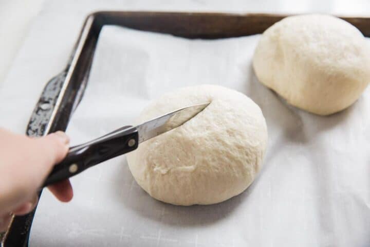 cutting an X on top of dough ball with sharp knife 