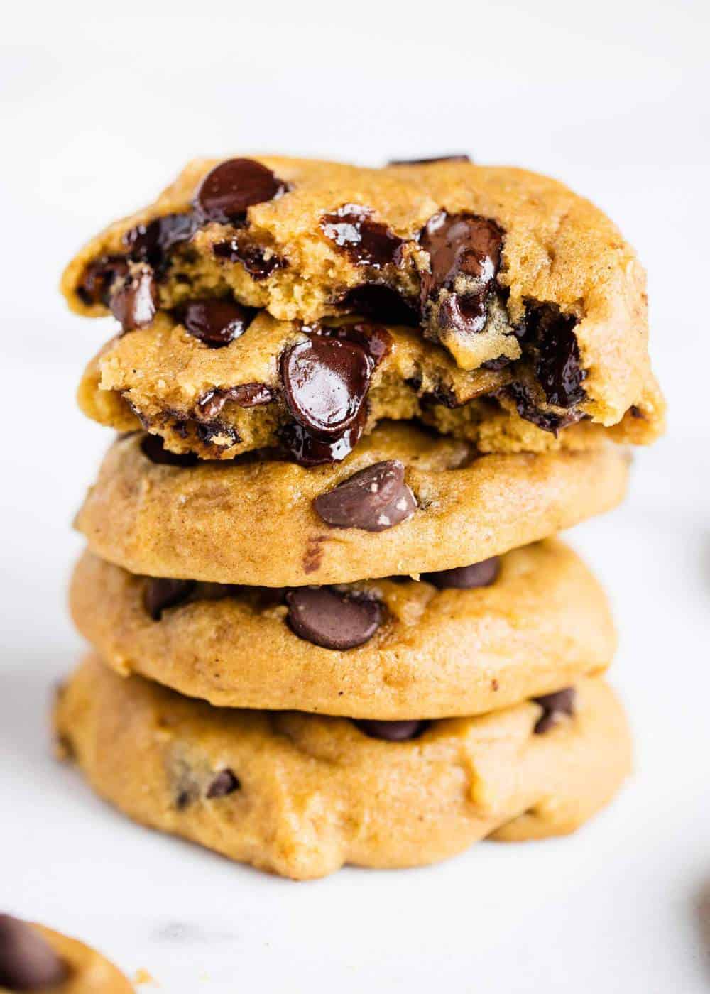 Pumpkin cookies stacked on the top of each other with a bite taken out. 