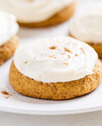 Pumpkin cookies with cream cheese frosting on a plate.