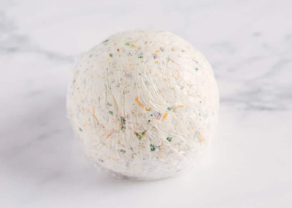 Bacon ranch cheese ball covered in plastic wrap.