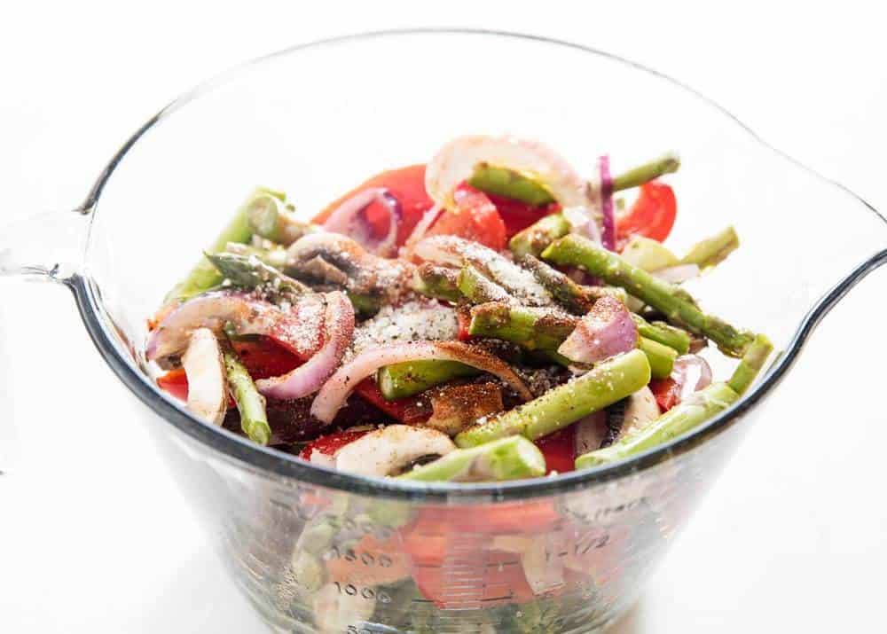 Raw vegetables in a glass measuring bowl with spices on top.