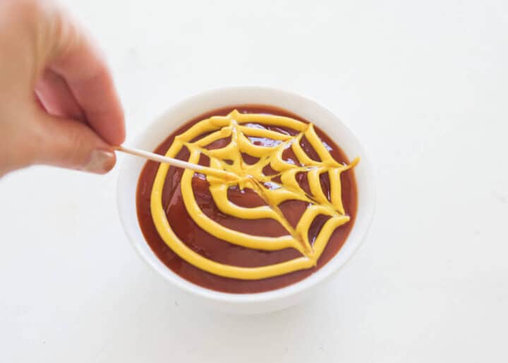 These mummy hot dogs are the easiest Halloween appetizer that takes only 2 ingredients to make! So fun, festive and delicious. Serve with spooky spider web sauce for the ultimate Halloween experience! spider web ketchup and mustard sauce