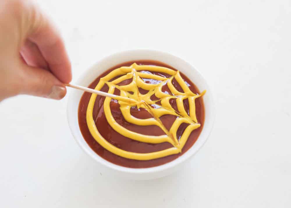 These mummy hot dogs are the easiest Halloween appetizer that takes only 2 ingredients to make! So fun, festive and delicious. Serve with spooky spider web sauce for the ultimate Halloween experience! Spider web ketchup and mustard sauce.
