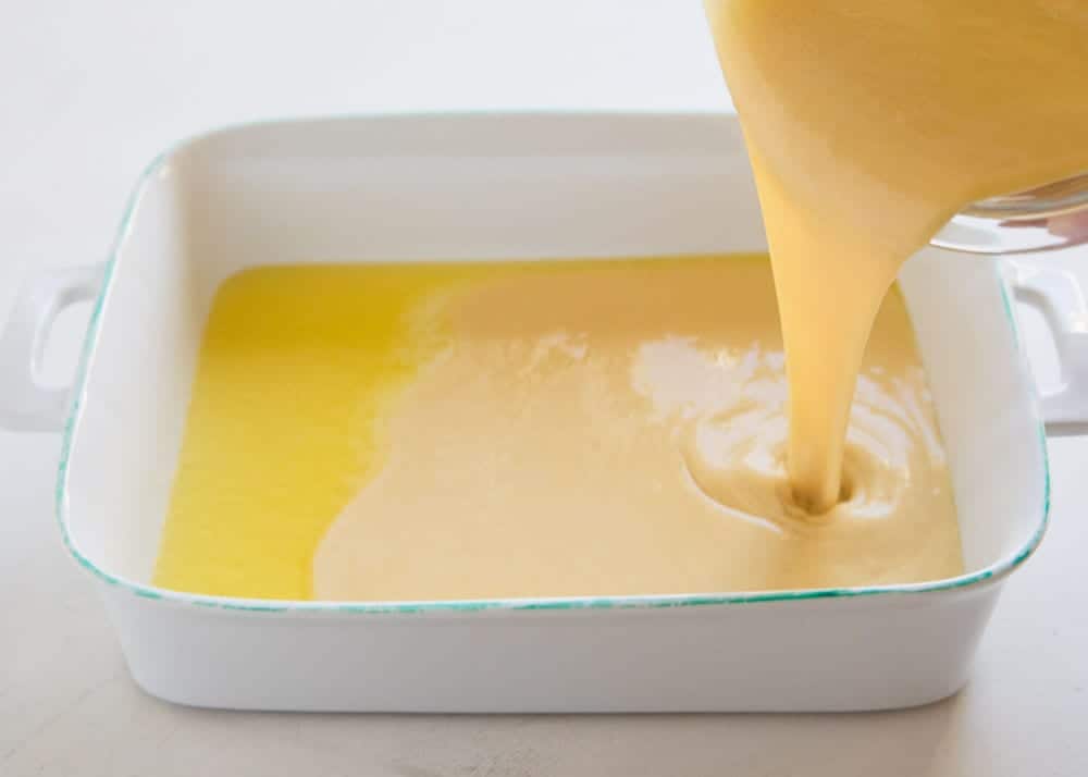 Pouring german pancake batter into a baking dish.