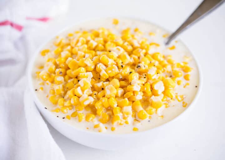 creamed corn in a white bowl with a spoon 