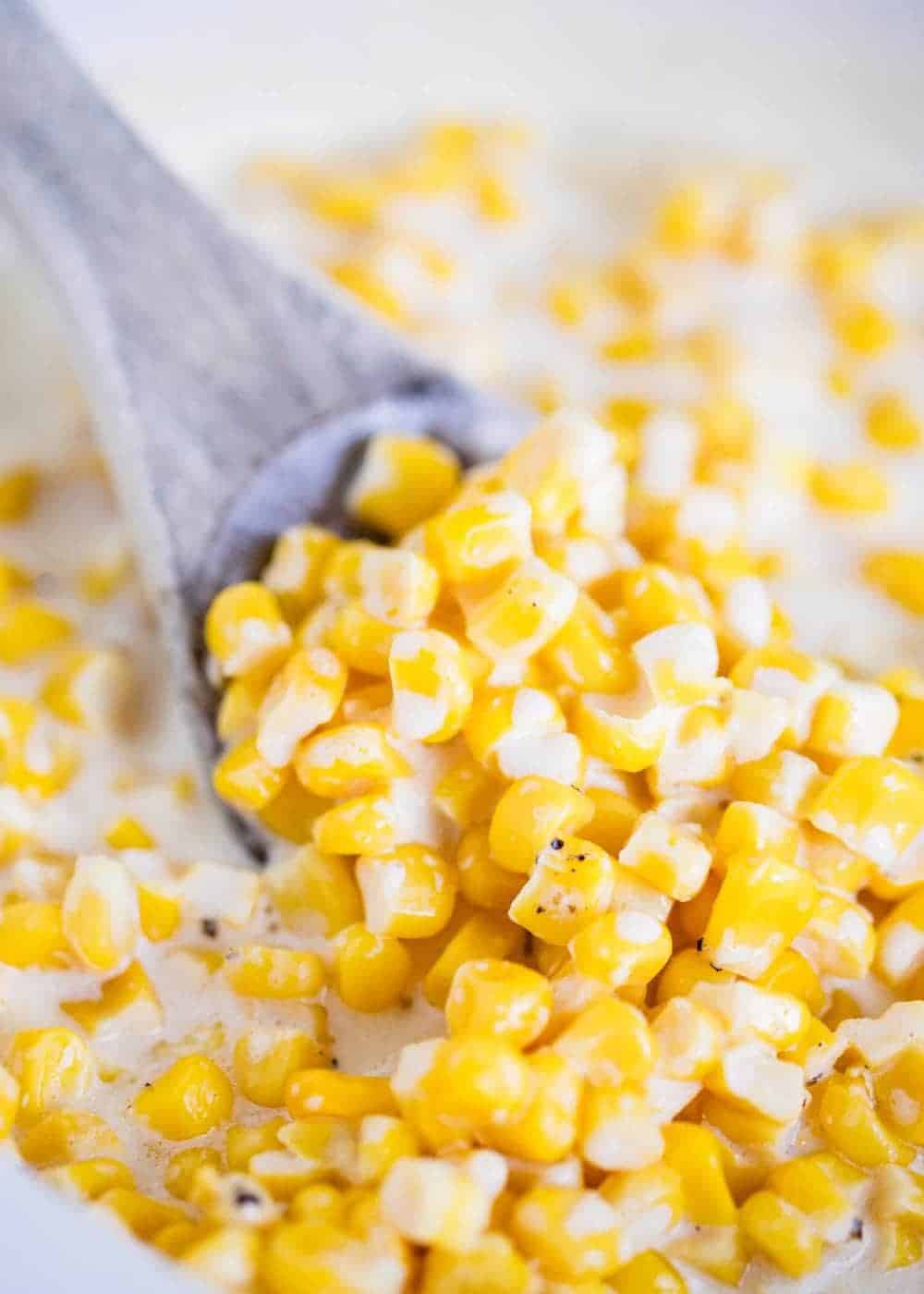 Creamed corn with a wooden spoon.