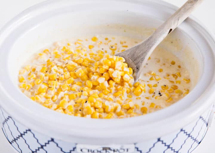 crockpot creamed corn with a wooden spoon 