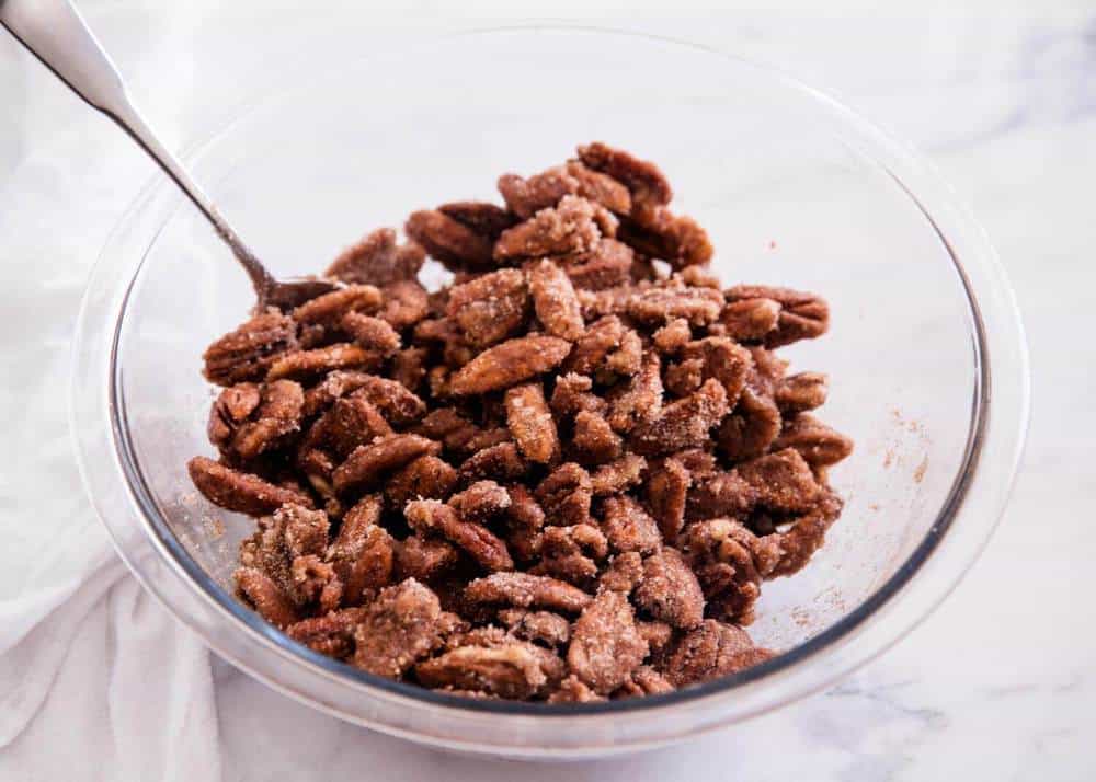 Mixing candied pecans in glass bowl.