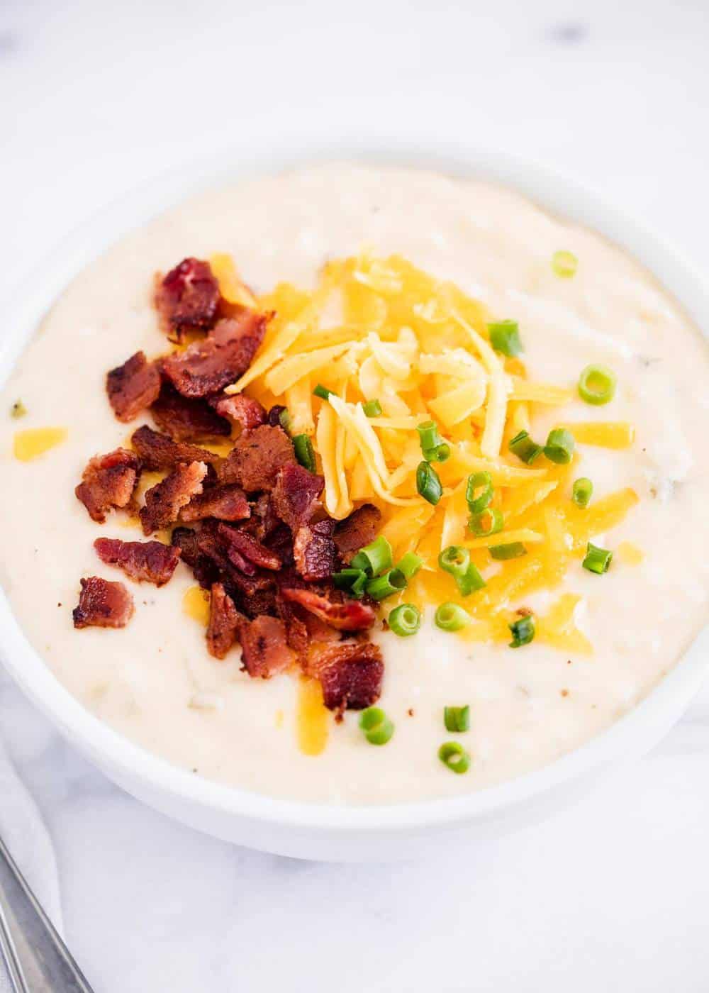 bowl of hash brown potato soup with bacon, cheese and green onion 